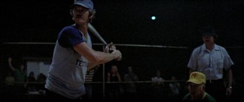 Movie still from “Norma Rae” (1979), directed by Martin Ritt – A man holding a baseball bat while standing on a baseball field; Medium shot, Over the shoulder angle