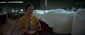 Movie still from “Norma Rae” (1979), directed by Martin Ritt – A woman in a yellow jacket writing on a piece of paper; Medium shot, Low angle