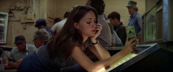 Movie still from “Norma Rae” (1979), directed by Martin Ritt – A woman sitting at a table with a book in front of her face; Close Up shot, High angle