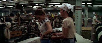 Movie still from “Norma Rae” (1979), directed by Martin Ritt – Two women are standing in an industrial setting; Medium shot, High angle