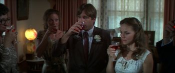 Movie still from “Norma Rae” (1979), directed by Martin Ritt – A man in a suit drinking a glass of red wine; Medium shot, Over the shoulder angle