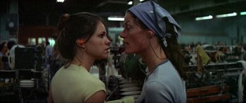 Movie still from “Norma Rae” (1979), directed by Martin Ritt – Two women are facing each other with ear buds in their ears; Close Up shot, Over the shoulder angle