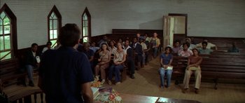 Movie still from “Norma Rae” (1979), directed by Martin Ritt – A group of people sitting in front of a man; Wide shot, High angle
