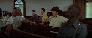 Movie still from “Norma Rae” (1979), directed by Martin Ritt – A group of men sitting in a row in a church; Medium shot, Over the shoulder angle
