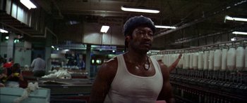 Movie still from “Norma Rae” (1979), directed by Martin Ritt – A man in a white tank top wearing a hat; Medium shot, Low angle