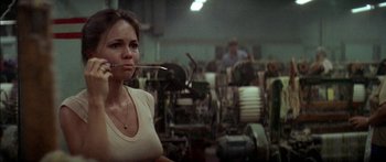 Movie still from “Norma Rae” (1979), directed by Martin Ritt – A woman is standing in front of a machine in a factory; Close Up shot, Low angle