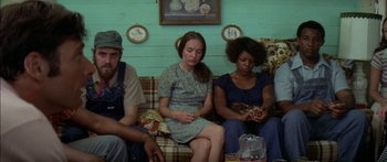 Movie still from “Norma Rae” (1979), directed by Martin Ritt – A group of people sitting on a couch in a living room; Medium shot, High angle