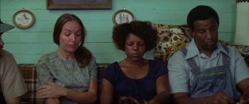 Movie still from “Norma Rae” (1979), directed by Martin Ritt – A woman sitting on a couch next to two other people; Medium shot, High angle