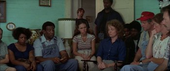 Movie still from “Norma Rae” (1979), directed by Martin Ritt – A group of people sitting in a living room together; Medium shot, Over the shoulder angle