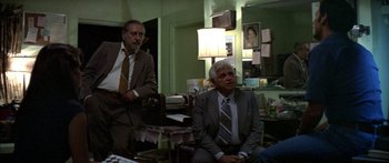 Movie still from “Norma Rae” (1979), directed by Martin Ritt – Two men in suits sitting in a living room; Medium shot, Over the shoulder angle