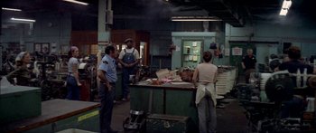 Movie still from “Norma Rae” (1979), directed by Martin Ritt – A group of people standing around a table in a room; Wide shot, High angle