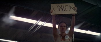 Movie still from “Norma Rae” (1979), directed by Martin Ritt – A woman holding up a sign that says " unions "; Medium shot, Low angle