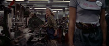 Movie still from “Norma Rae” (1979), directed by Martin Ritt – A woman standing next to a machine in a room; Wide shot, High angle