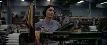 Movie still from “Norma Rae” (1979), directed by Martin Ritt – A woman standing in front of a spinning wheel; Close Up shot, Low angle