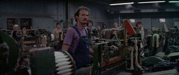 Movie still from “Norma Rae” (1979), directed by Martin Ritt – A man standing in front of machines in a room; Medium shot, High angle