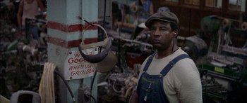 Movie still from “Norma Rae” (1979), directed by Martin Ritt – A man standing in front of a grinding machine in a shop; Close Up shot, Low angle