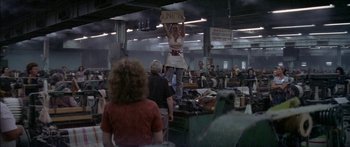Movie still from “Norma Rae” (1979), directed by Martin Ritt – A woman in an apron holds a sign above her head; Wide shot, High angle