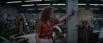 Movie still from “Norma Rae” (1979), directed by Martin Ritt – A woman in a red shirt and white skirt is standing in a room; Medium shot, Low angle