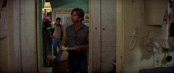 Movie still from “Norma Rae” (1979), directed by Martin Ritt – A man holding a plate in a room with a woman; Medium shot, Low angle