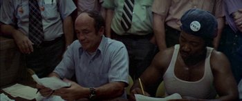 Movie still from “Norma Rae” (1979), directed by Martin Ritt – A man sitting in front of a group of people; Medium shot, High angle