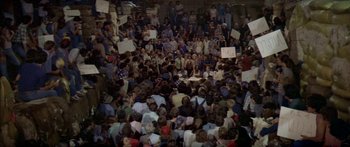 Movie still from “Norma Rae” (1979), directed by Martin Ritt – A crowd of people sitting and standing in front of a building; Extreme Wide shot, Overhead angle