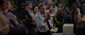Movie still from “Norma Rae” (1979), directed by Martin Ritt – A man is holding a megaphone in front of a crowd; Medium shot, High angle