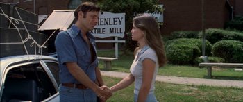 Movie still from “Norma Rae” (1979), directed by Martin Ritt – A man and a woman holding hands in front of a sign; Medium shot, Over the shoulder angle