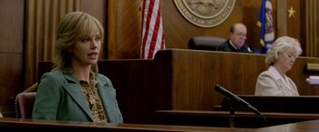 Movie still from “North Country” (2005), directed by Niki Caro – A woman sitting in front of a microphone in a courtroom; Medium shot, Over the shoulder angle