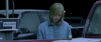 Movie still from “North Country” (2005), directed by Niki Caro – A woman sitting at a table in a parking lot at night; Medium shot, Over the shoulder angle