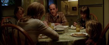 Movie still from “North Country” (2005), directed by Niki Caro – Three people sitting at a dinner table with plates of food on the table; Medium shot, Over the shoulder angle