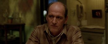 Movie still from “North Country” (2005), directed by Niki Caro – An older man with a bald head sitting in a chair; Close Up shot, Over the shoulder angle