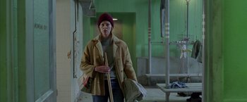 Movie still from “North Country” (2005), directed by Niki Caro – A woman in a brown coat and a red hat holding a stick; Medium shot, High angle