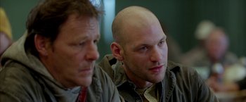 Movie still from “North Country” (2005), directed by Niki Caro – Two men sitting next to each other in front of a wall; Close Up shot, Low angle