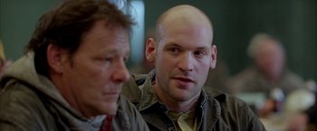 Movie still from “North Country” (2005), directed by Niki Caro – A man with a bald head is looking at another man; Close Up shot, Over the shoulder angle