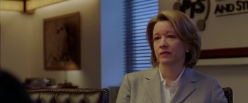 Movie still from “North Country” (2005), directed by Niki Caro – A woman sitting in a chair wearing a suit; Close Up shot, Over the shoulder angle