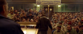 Movie still from “North Country” (2005), directed by Niki Caro – A group of people sitting and standing in front of a crowd; Wide shot, High angle