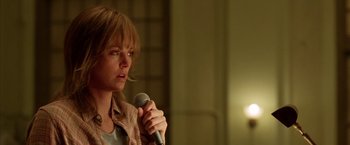 Movie still from “North Country” (2005), directed by Niki Caro – A person holding a microphone in a room; Close Up shot, Over the shoulder angle