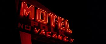 Movie still from “North Country” (2005), directed by Niki Caro – A neon sign that reads " motel polk vacancy "; Wide shot, Low angle