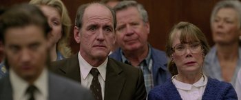 Movie still from “North Country” (2005), directed by Niki Caro – A man in a suit and tie in front of a crowd; Close Up shot, Over the shoulder angle