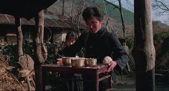 Movie still from “North Korean Partisan in South Korea” (1990), directed by Jeong Ji-yeong – A man and a woman standing next to a table; Medium shot, Low angle