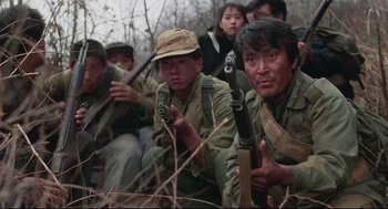 Movie still from “North Korean Partisan in South Korea” (1990), directed by Jeong Ji-yeong – A group of people in the woods holding guns; Medium shot, High angle
