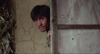Movie still from “North Korean Partisan in South Korea” (1990), directed by Jeong Ji-yeong – A man peeking out from behind a wall; Close Up shot, Low angle