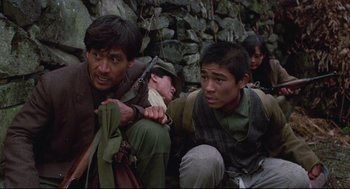 Movie still from “North Korean Partisan in South Korea” (1990), directed by Jeong Ji-yeong – A group of men sitting next to each other on the ground; Medium shot, High angle