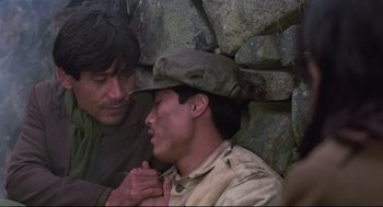 Movie still from “North Korean Partisan in South Korea” (1990), directed by Jeong Ji-yeong – Two men are standing next to a stone wall; Close Up shot, Over the shoulder angle