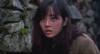 Movie still from “North Korean Partisan in South Korea” (1990), directed by Jeong Ji-yeong – A young woman with long black hair wearing a brown jacket; Close Up shot, Low angle