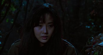 Movie still from “North Korean Partisan in South Korea” (1990), directed by Jeong Ji-yeong – A woman with long black hair is in the dark; Close Up shot, Low angle