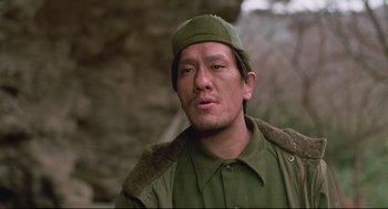 Movie still from “North Korean Partisan in South Korea” (1990), directed by Jeong Ji-yeong – A man wearing a green hat and a green jacket; Close Up shot, Low angle