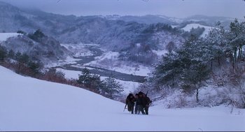 Movie still from “North Korean Partisan in South Korea” (1990), directed by Jeong Ji-yeong – A group of skiers standing on top of a snow covered slope; Extreme Wide shot, High angle