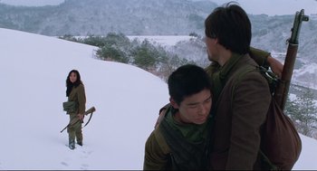 Movie still from “North Korean Partisan in South Korea” (1990), directed by Jeong Ji-yeong – Two men are walking in the snow while another man holds a bow; Medium shot, Over the shoulder angle