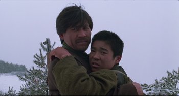 Movie still from “North Korean Partisan in South Korea” (1990), directed by Jeong Ji-yeong – A man and a young boy hugging each other; Close Up shot, Low angle